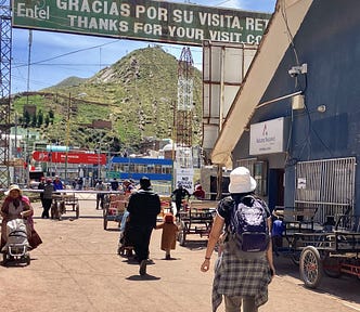 The author’s wife walks past a “thank you for visiting Bolivia” sign.