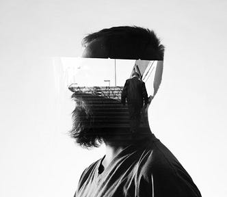 A grayscale side view of a bearded man with an image of someone walking across his head