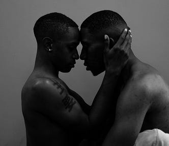 Two shirtless Black Men, face to face, gazing lovingly at each other.