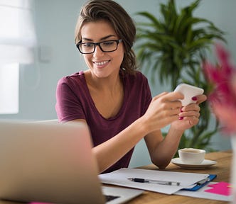 A smiling writer sits in front of her laptop with a sense of achievement.