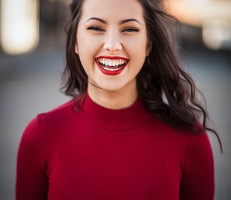 Long haired, brunette, Caucasian woman, wearing a long sleeve red pull-over smiling for the camera.