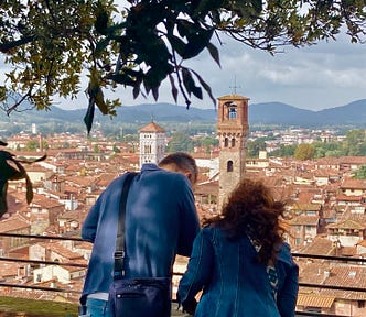 A man and woman look down on the rooftops and views of Lucca