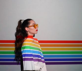 Teen girl with a rainbow running behind her and over her sweater.