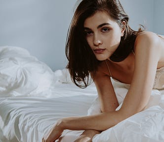 Woman Lying on White Bedding