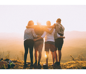 Four friends standing together looking at a sunset