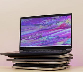 Six laptops stacked on top of each other. The top one is open displaying a purple wallpaper.
