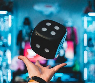 A hand throwing a large black dice.