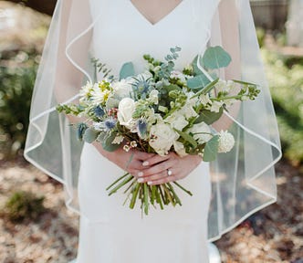 woman in wedding dress holding bouquet of white flowers and eucalyptus