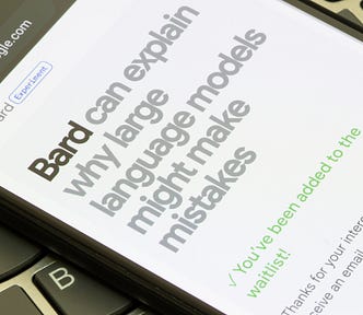 A photo of a phone resting on a laptop keyboard. The phone is open to a browser page, “bard.google.com”, and the page header reads “Bard can explain why large language models might make mistakes” before showing a confirmation that the user has been added to a waitlist.