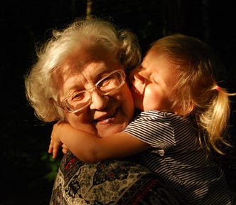 A smiling grandma enjoys the hugs and smiles of her young granddaughter