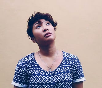 Woman in a blue patterned t-shirt looks up at the sky