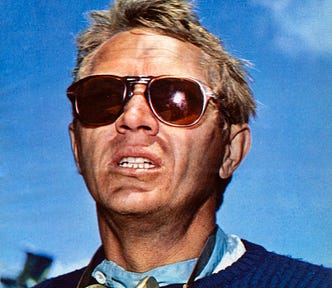 Here a navy blue crew-neck sweater-clad Steve McQueen participates in a racing event in Southern California in the mid-1960s