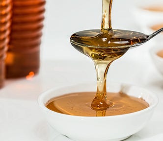 closeup photograph of maple syrup being poured into a bowl and spoon