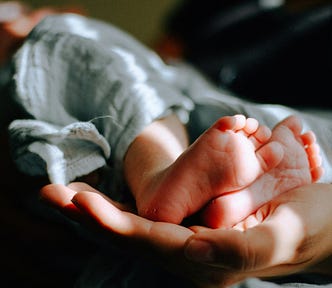 A newborn baby’s feet cradled in a mother’s hand.