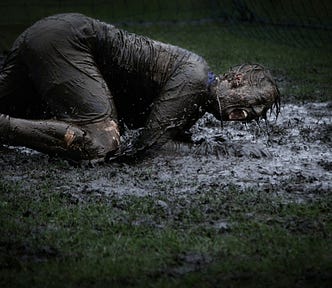 man lying in a pool of mud