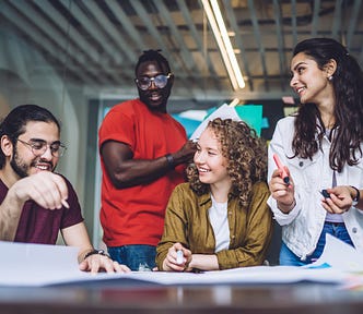 Two young men and two young women are talking in an office.