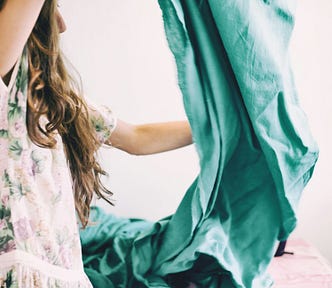 A woman with long hair hold up a large piece of green fabric