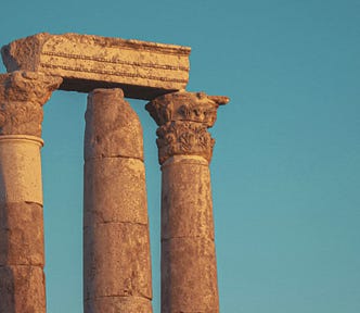 3 orange Roman columns against a plain teal sky