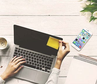 Woman opening a laptop on a desk.