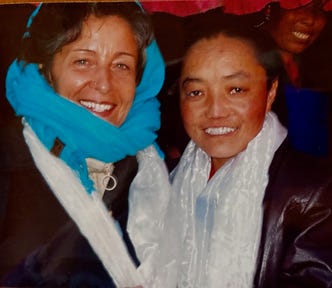 A nun standing with the author outside a rural monastery in Tibet. Both heavily clothed due to high altitude cold.