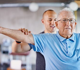 A physiotherapist helping a senior man with weights.