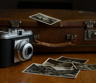 Vintage suitcase with camera and scattered black and white photographs