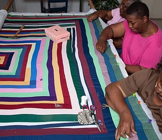 quiiters of Gee’s Bend working on a framed quilt together