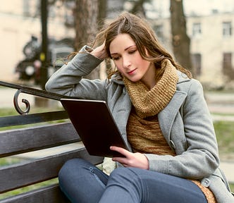 woman reading an ebook on her tablet in the park