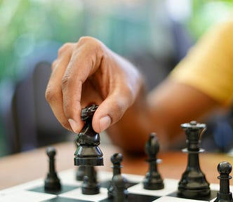 A person’s hand moves a chess piece across a chess board