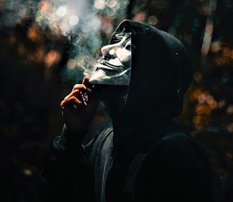 person wearing black hooded sweatshirt and white face mask smoky background