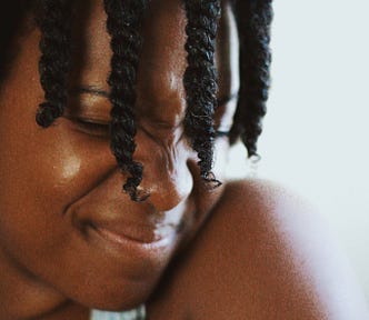 Photo of a young black woman with braids, grimacing with her eyes closed.