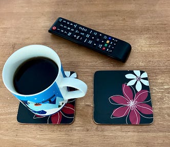 One coffee cup, two coasters, and a TV remote