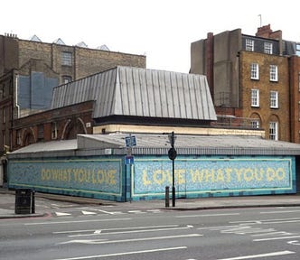 Two mosaic walls meeting at the corner of a city street. Both are pale blue with yellow lettering. One reads, “Do what you love,” and the other, “Love what you do.”