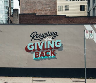 Building, at a street corner, in Granville area of Vancouver, BC, with the words “Recycling and Giving Back” painted upon the building exterior wall.