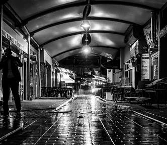 A night time street scene of a man walking home in the darkness in the rain on a wet evening