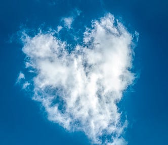 Heart-shaped white cloud against a blue sky.