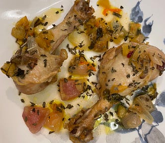 Two beautiful chicken drumsticks with fruits, vegetables, and oily juice on a plate
