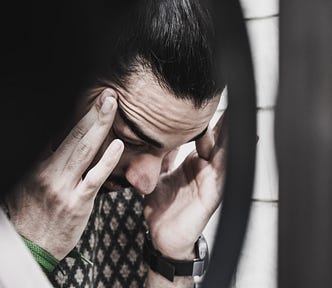 Man holding his temples looking down.