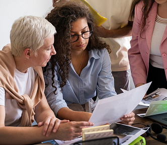 A photo of two women studying a document together.