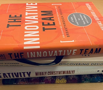 A stack of design books on a wooden desk