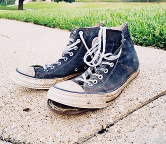 A pair of high-top sneakers in terrible shape.