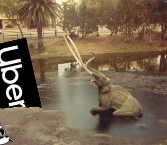 The sinking mammoth exhibition at the La Brea Tar Pits; next to the doomed pachyderm is the Uber logo, also mired in the tar. Monopoly’s Rich Uncle Pennybags is partially in the bottom left corner of the frame, running away with a bag of money. Image: Tarcil (modified) CC BY-SA: https://creativecommons.org/licenses/by-sa/4.0/deed.en