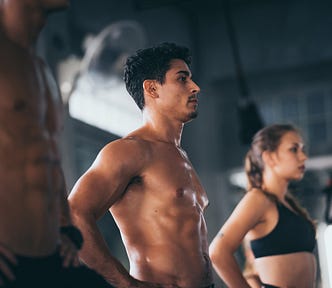 Two fit men and a woman working out at the gym.