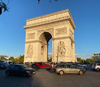 A large arch is surrounded by cars traveling around it