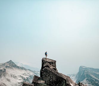 A guy standing on top of the mountain and overlooking the view