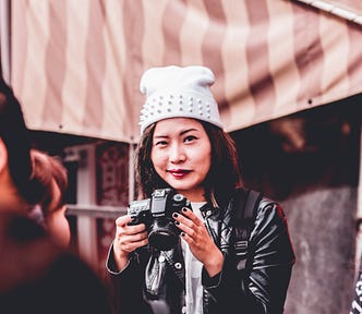 A lady smiling with a camera in her hands.