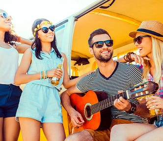 A man playing guitar in a yellow van surrounded by three women.