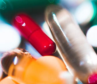 A collection of multicolored pills with a red one in focus