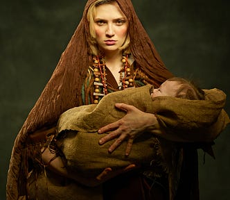 Solemn woman in old-fashioned clothes holding infant