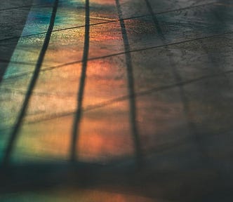 Soft bands of reflected light stretching across a stone floor, with faint parallel shadows and the surrounding space blurred.